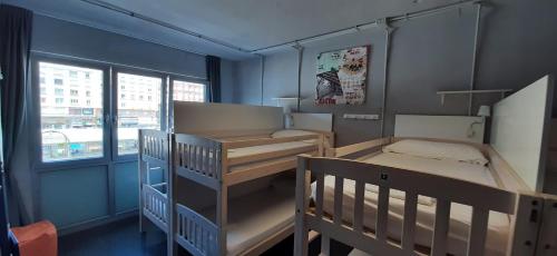 een kleine kamer met 2 stapelbedden en een raam bij Santander Central Hostel in Santander