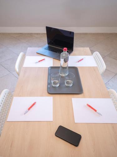 a table with papers and a bottle of water and pens at Hotel Jolly Roger in Pietra Ligure