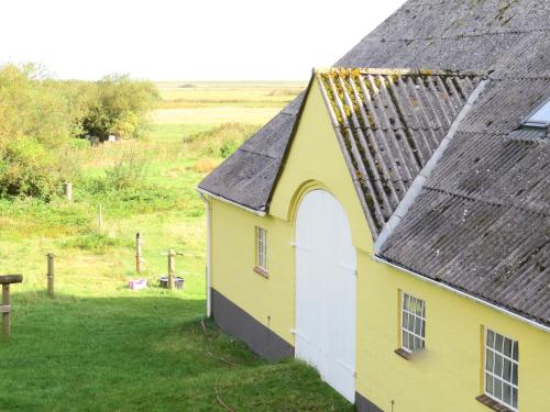 a yellow building with a black roof at Mandøgården in Ribe