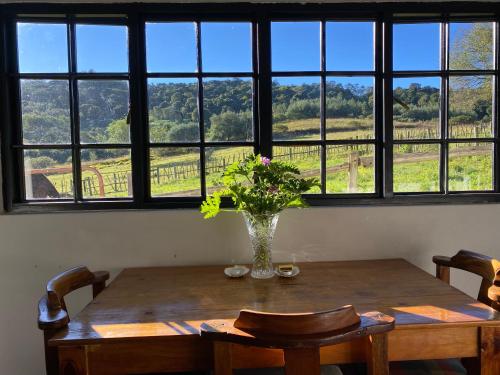 a vase of flowers on a wooden table in front of a window at Newstead Farm - Country Cottages in Curryʼs Post