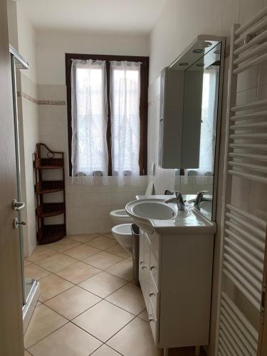 a bathroom with a sink and a toilet and a mirror at Appartamenti Sole e Lago in Gravedona