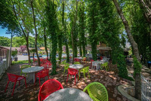 a group of tables and chairs under trees at Sebastiano Resort in Lezhë