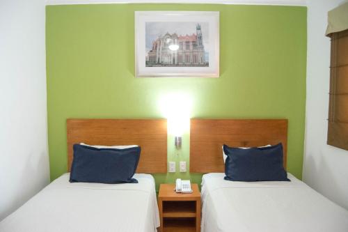 two beds in a room with green walls at Hotel River Poliforum in León