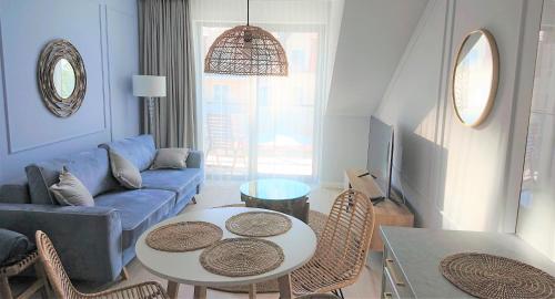 ein Wohnzimmer mit einem blauen Sofa und einem Tisch in der Unterkunft Niechorze Amber Sunset apartment in Niechorze