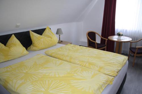 a bedroom with a bed with yellow sheets and a table at Pension / Ferienwohnung Allebrodt in Lennestadt