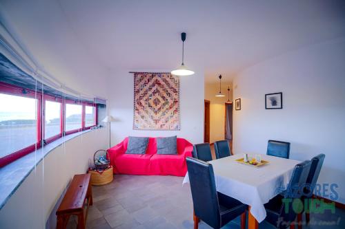 a living room with a table and a red couch at Boina de Vento in Santa Cruz da Graciosa