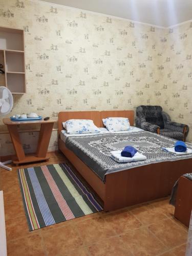 a small bedroom with a bed and a chair at Guest House Komsomolskiy in Anapa