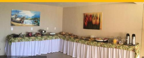 einen Tisch in einem Zimmer mit einem weißen Tischtuch in der Unterkunft Marupiara Suítes Muro alto Apts 319 e 224 in Porto De Galinhas