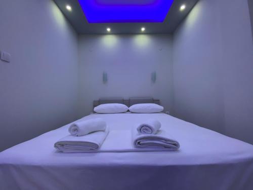 Una cama con sábanas blancas y toallas. en Nikolaidis Apartments, en Nea Plagia