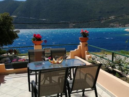 a table and chairs on a balcony with a view of the water at Ilios studios in Vasiliki