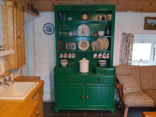 a green cabinet with plates on it in a kitchen at CherryTreeCottage - Cosy 19thCentury Pet Friendly in Claragh
