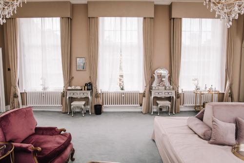 a living room with a couch and chairs and windows at Hawkstone Hall Hotel & Gardens in Shrewsbury