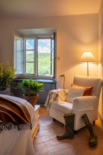 a room with a bed and a chair and a window at Castello di Volpaia in Radda in Chianti