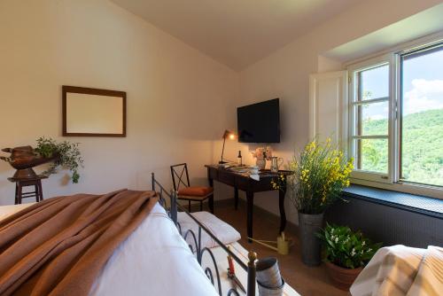 a bedroom with a bed and a desk and window at Castello di Volpaia in Radda in Chianti
