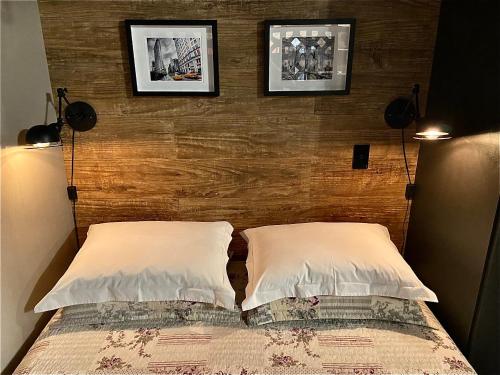 ein Bett mit zwei Kissen und zwei Bildern an der Wand in der Unterkunft Saint Moritz Flat Particular com Garagem, Estilo Industrial no Coração de Brasília in Brasilia