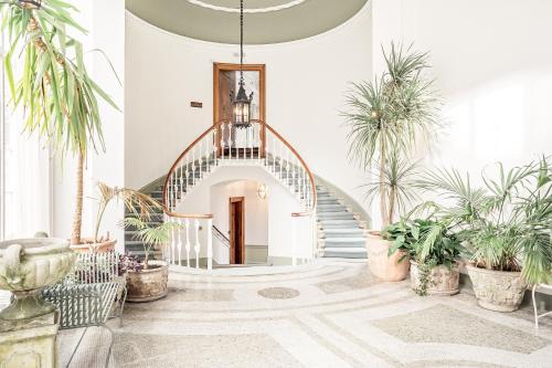 a hallway with a spiral staircase with potted plants at Hawkstone Hall Hotel & Gardens in Shrewsbury