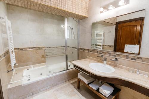 a bathroom with a sink and a tub and a mirror at Chalten Suites Hotel in El Chalten