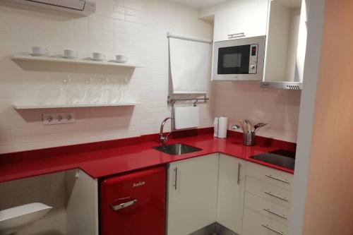 cocina roja con fregadero y microondas en M1 Cool Loft 1 min walk to metro 15 min center by metro, en Esplugues de Llobregat