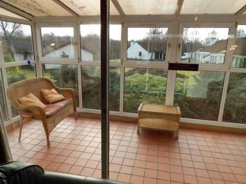 a screened in porch with a chair and a table at Macdonald Spey Valley Resort in Aviemore