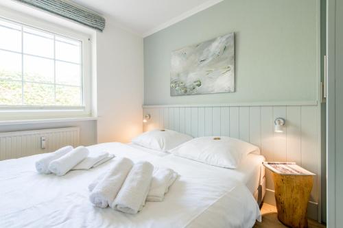 een slaapkamer met een wit bed en handdoeken bij Haus Friesische Strasse 25a Whg 1 in Westerland