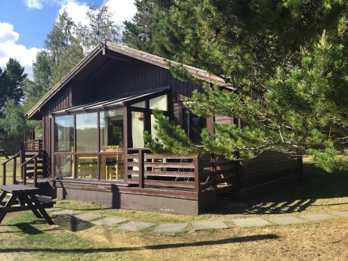 a log cabin with a picnic table in front of it at Macdonald Spey Valley Resort in Aviemore