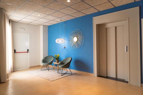 a room with two chairs and a blue wall at Hotel Aubí in Sant Antoni de Calonge