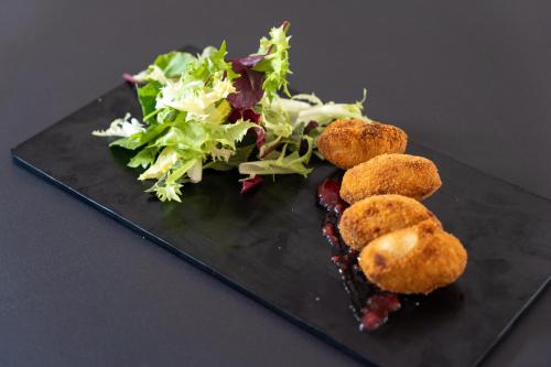 a plate with a salad and three fried food at Hotel Aubí in Sant Antoni de Calonge