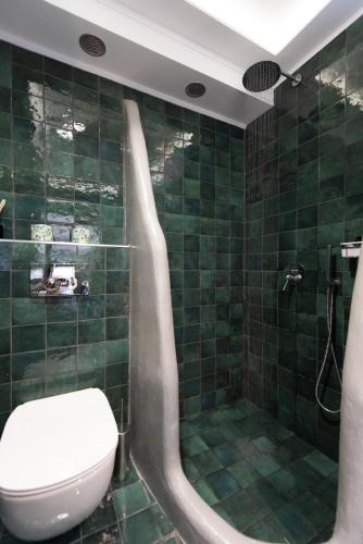 a green tiled bathroom with a toilet and a shower at The Be House in Sifnos