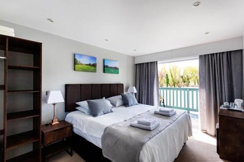 The Vale Golf & Country Club في Bishampton: غرفة نوم عليها سرير وفوط
