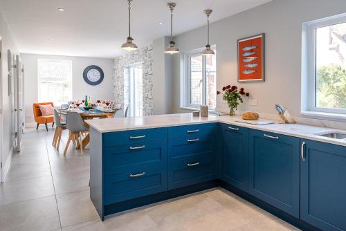 a kitchen with blue cabinets and a dining room at The Grange, Aldeburgh in Aldeburgh