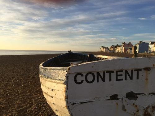 a boat sitting on the beach next to the ocean at The Grange, Aldeburgh in Aldeburgh