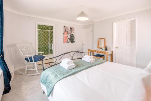 a white bedroom with a bed and a chair at The Grange, Aldeburgh in Aldeburgh