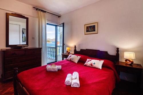 a bedroom with a red bed with slippers on it at Holiday Home Malinina in Mali Iž