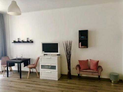 ein Wohnzimmer mit einem TV, einem Tisch und Stühlen in der Unterkunft JA 12 Apartment in Budapest