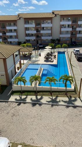 einem großen Pool mit Palmen vor einem Gebäude in der Unterkunft Apartamento Guarajuba in Camaçari