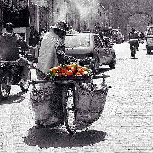 a man riding a bike with a basket of fruit at La Sultana Marrakech in Marrakesh