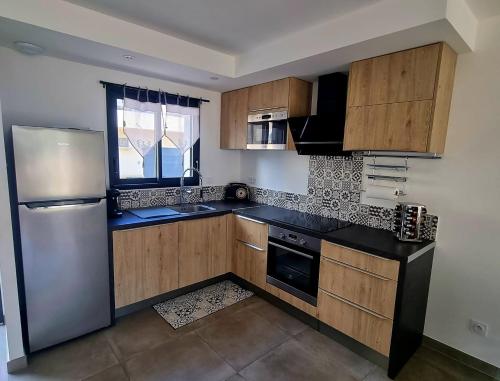 une cuisine avec des armoires en bois et un réfrigérateur en acier inoxydable dans l'établissement Maison U nidu à 500m de la mer, à Cervione