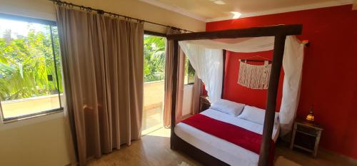 a bedroom with a canopy bed and a window at Hotel Ferrugem Eco Village in Garopaba