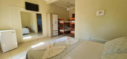 a room with a bed and a tv in it at Hotel Ferrugem Eco Village in Garopaba