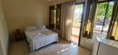a small bedroom with a bed and a window at Hotel Ferrugem Eco Village in Garopaba