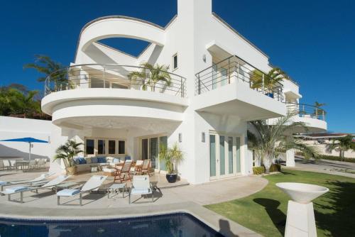 a white house with a swimming pool in front of it at Exquisite Hilltop Villa with Luxurious Modern Design, Sweeping Ocean Views & Sparkling Infinity Pool in Playa Flamingo