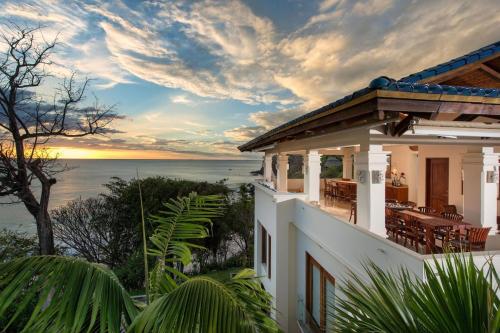 a house with a view of the ocean at sunset at Exquisite Hilltop Villa with Luxurious Modern Design, Sweeping Ocean Views & Sparkling Infinity Pool in Playa Flamingo