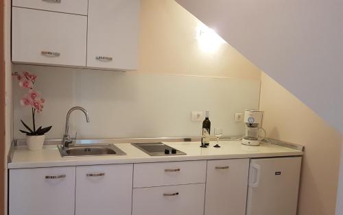 a kitchen with white cabinets and a sink at Apartmani Diva in Malinska