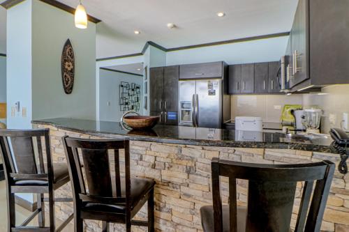 a kitchen with a bar with three bar stools at Diamante del Sol 602N in Jacó