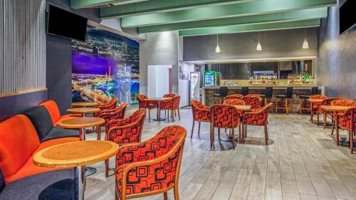 a restaurant with orange chairs and tables and a bar at CHN Hotel Monterrey Centro, Trademark Collection by Wyndham in Monterrey