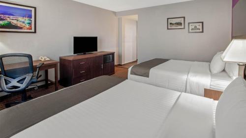 a hotel room with two beds and a desk and a television at CHN Hotel Monterrey Centro, Trademark Collection by Wyndham in Monterrey