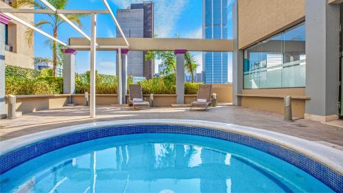 a swimming pool with two chairs and a building at CHN Hotel Monterrey Centro, Trademark Collection by Wyndham in Monterrey
