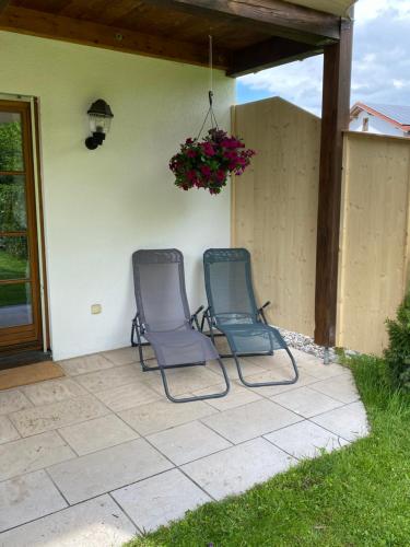 two chairs sitting on a patio in front of a house at Neurenovierte Ferienwohnung Franzl in Holzkirchen