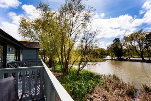 a house with a balcony next to a river at The Vale Golf & Country Club in Bishampton