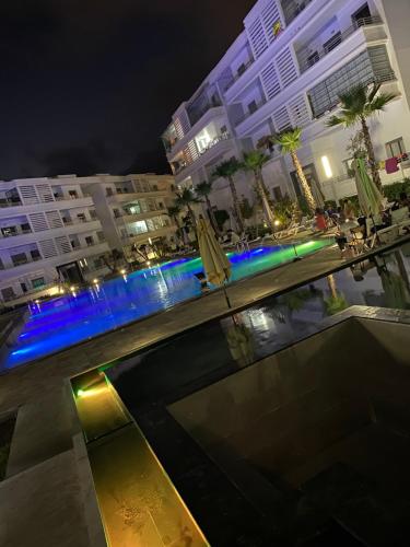 穆罕默迪耶Mansbay Beach, Vue sur Mer, accès Plage à pied, Mohammedia的一座夜间游泳池,有楼房